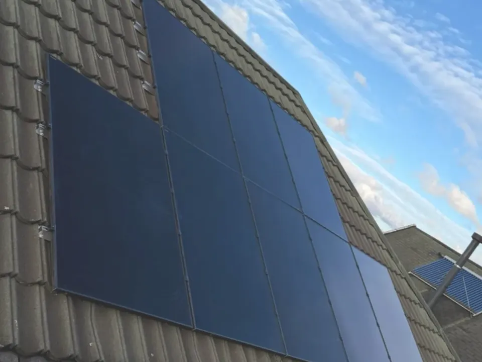 Close view of solar panels fitted across a pantile roof against a blue sky